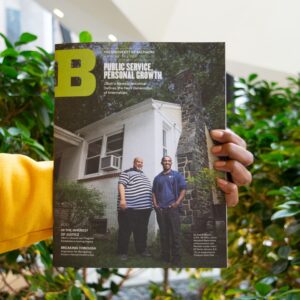 Someone holding the University of Baltimore Magazine with plants in the background.